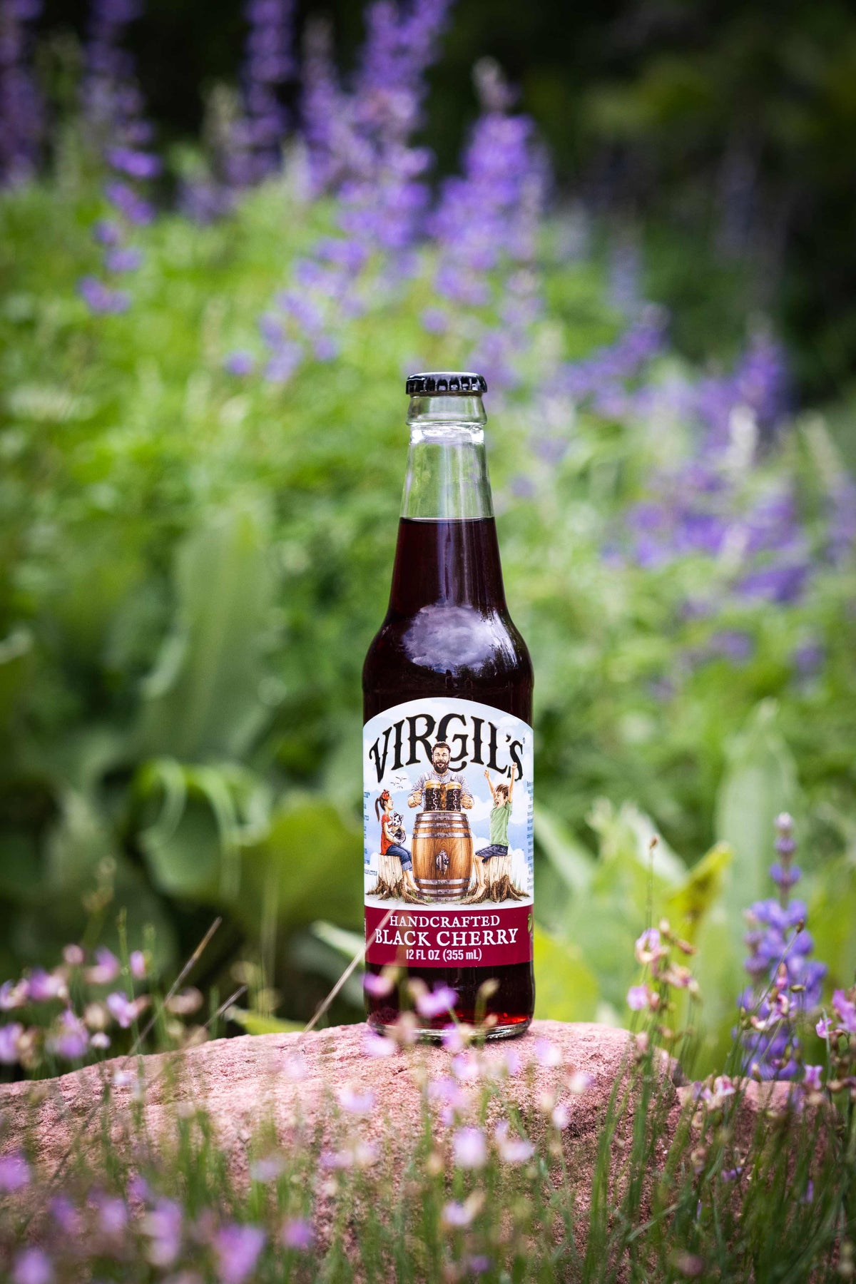 Bottle of Virgil's Black Cherry beer on a rock with a natural background