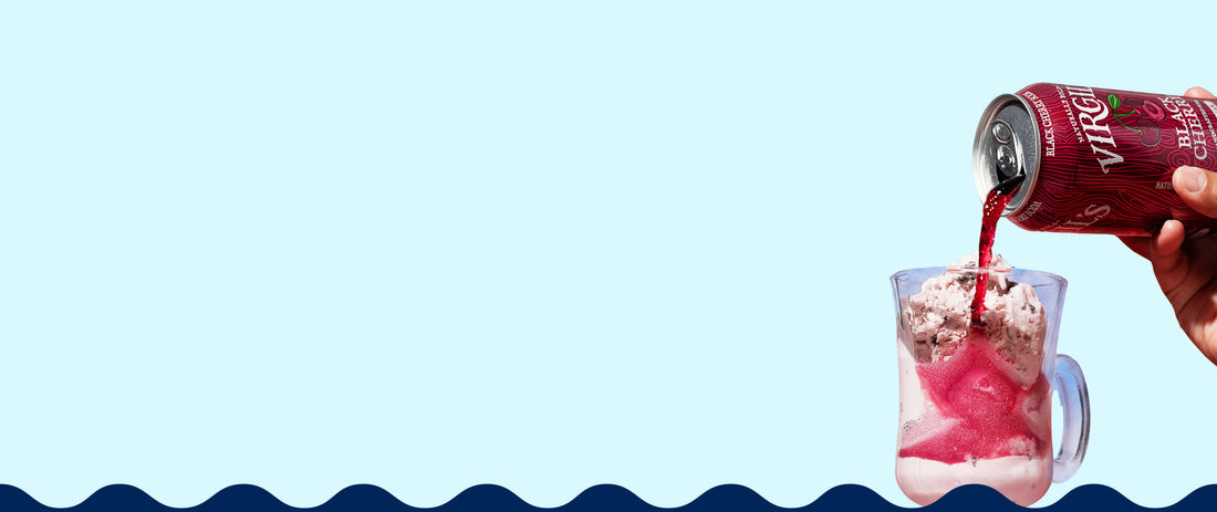 Person pouring virgil's black cherry soda from a can into a glass with ice cream against a light blue background